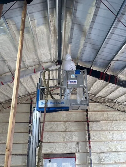 785 Insulation technician spraying closed-cell foam on a metal building roof deck from a lift